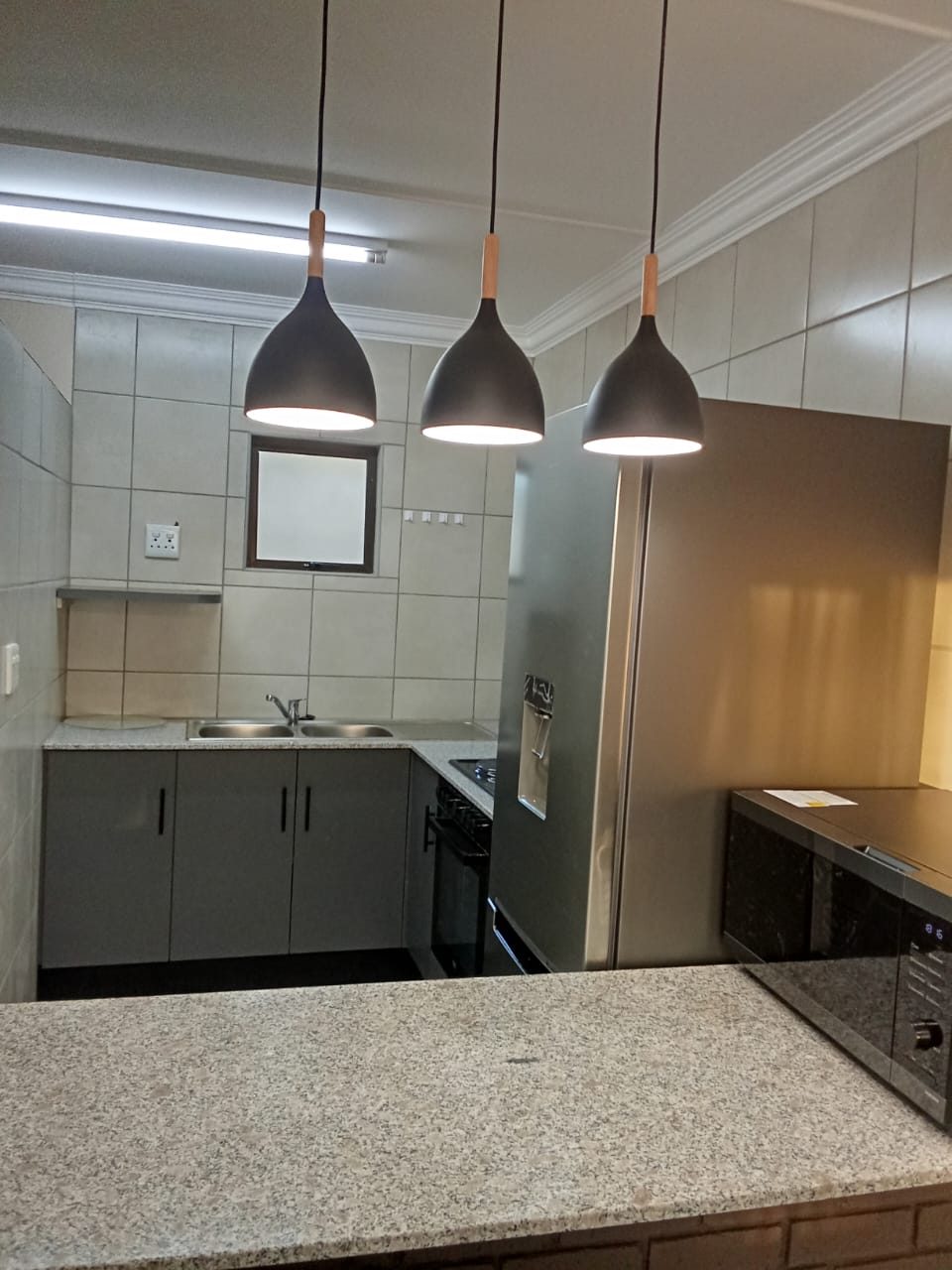 Renovated kitchen with granite countertops, pendant lights and new appliances